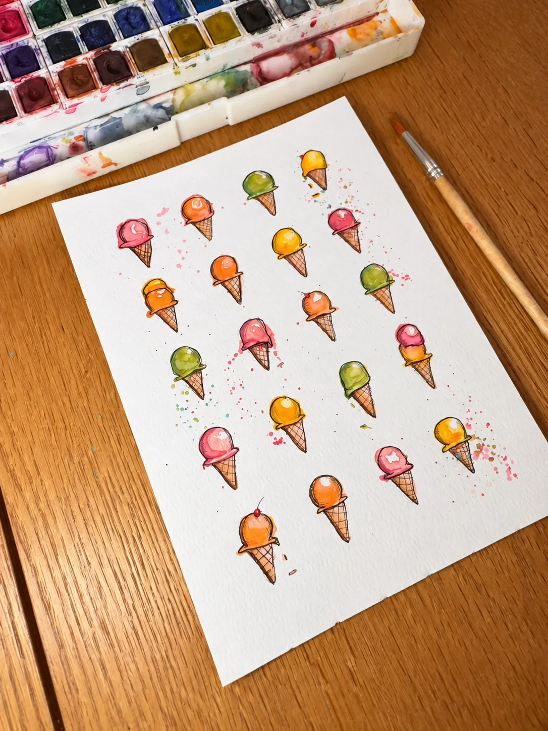 Ice Cream Social lying on a wooden worktable beside a watercolor palette and brush