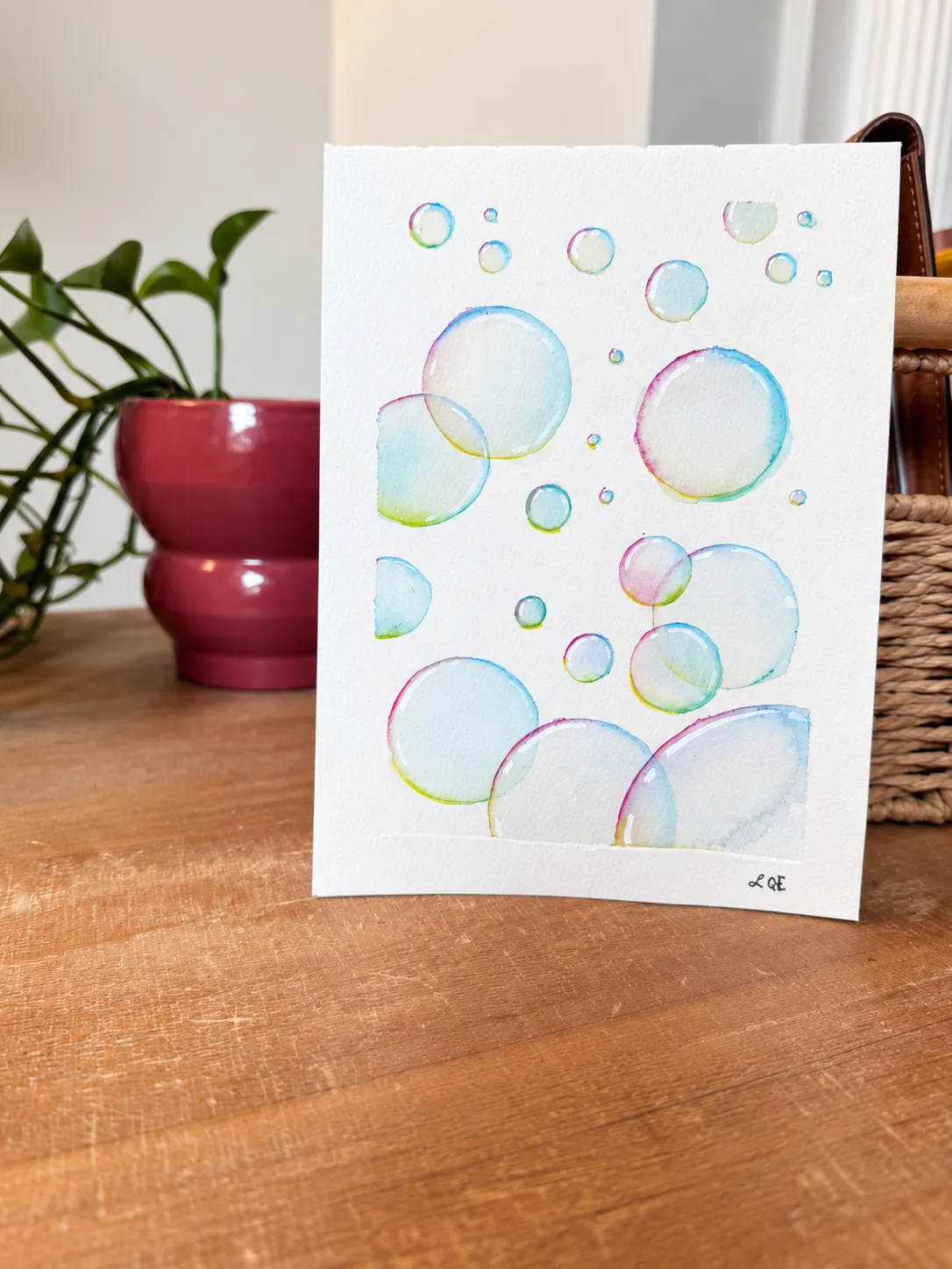Iridescent Bubbles standing beside a plant and woven basket